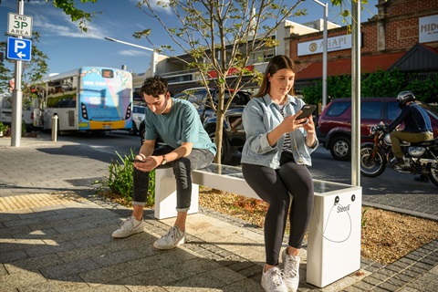 Two people sitting at phone charging station